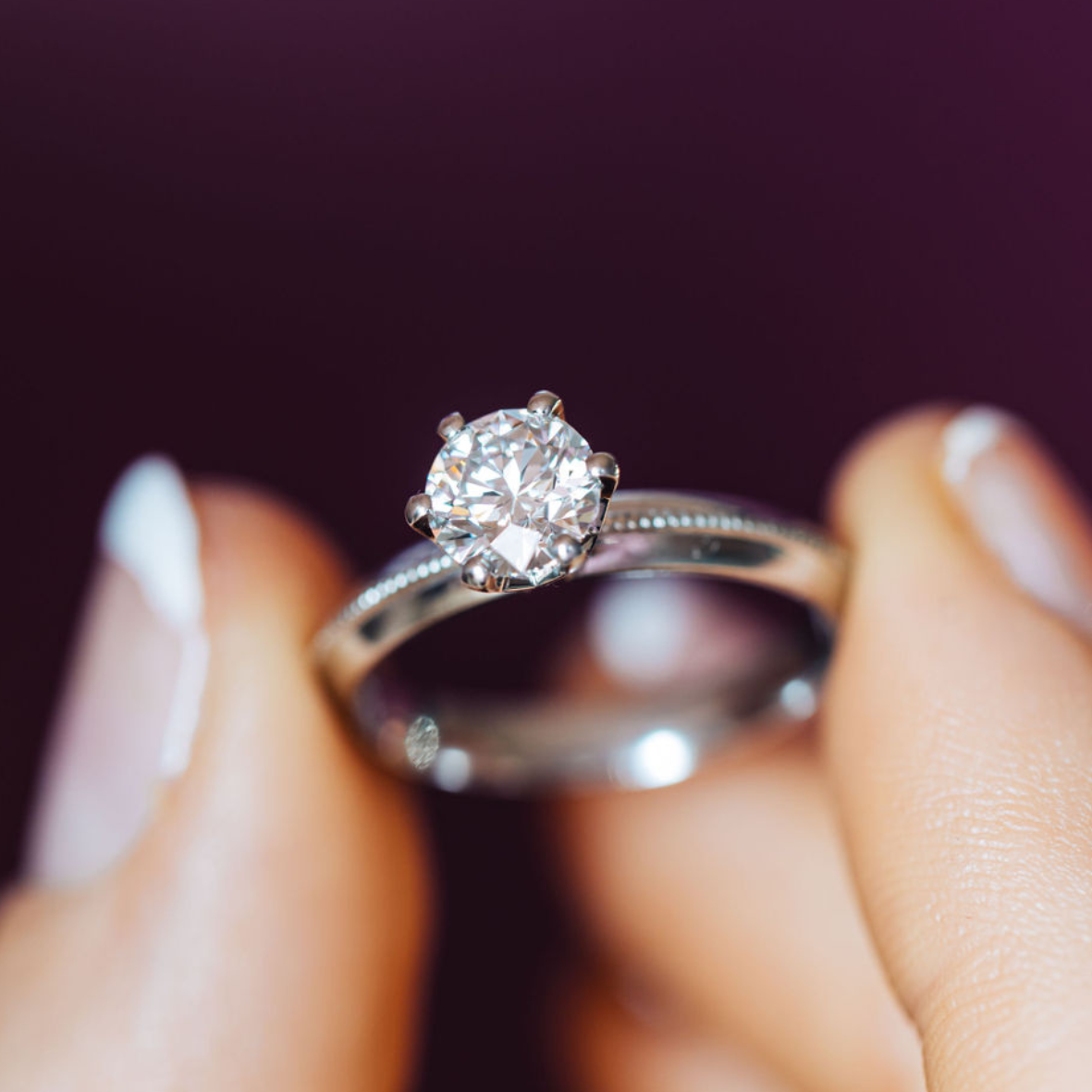 Close up of platinum ring with round brilliant cut diamonds being held by a persons hand