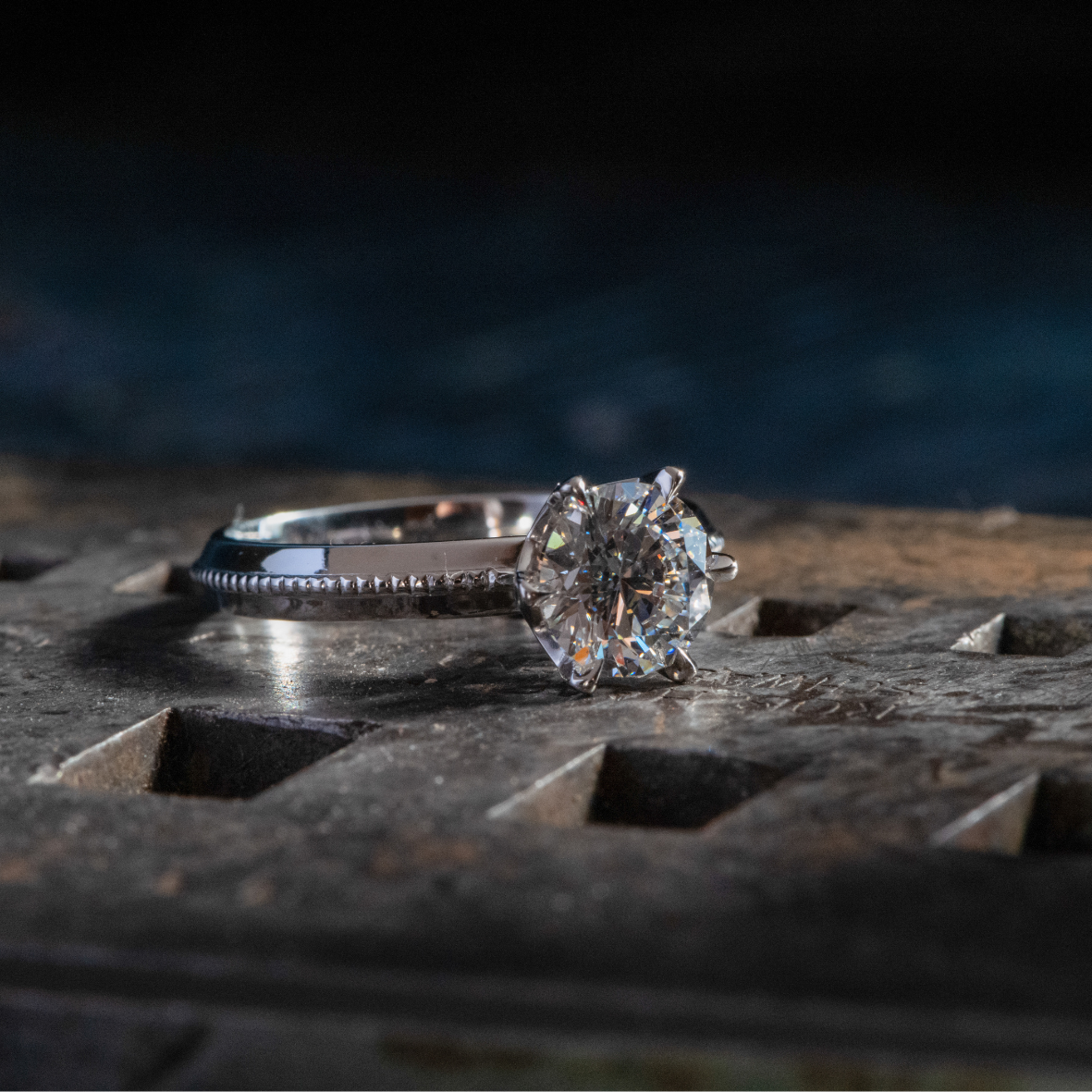 Close up of platinum ring with round brilliant cut diamonds with a mill grained detailing