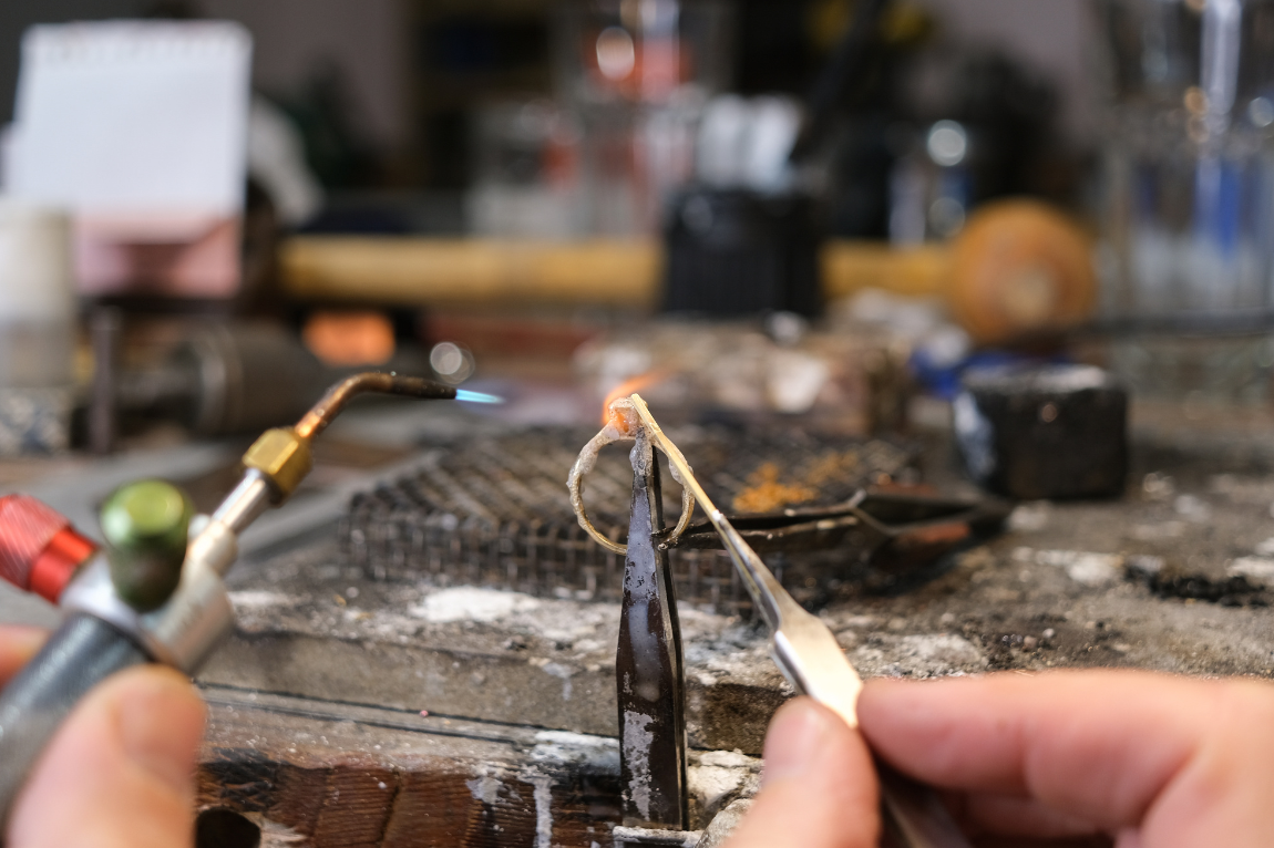 Close up of a jeweller re tipping a ring in his workshop.