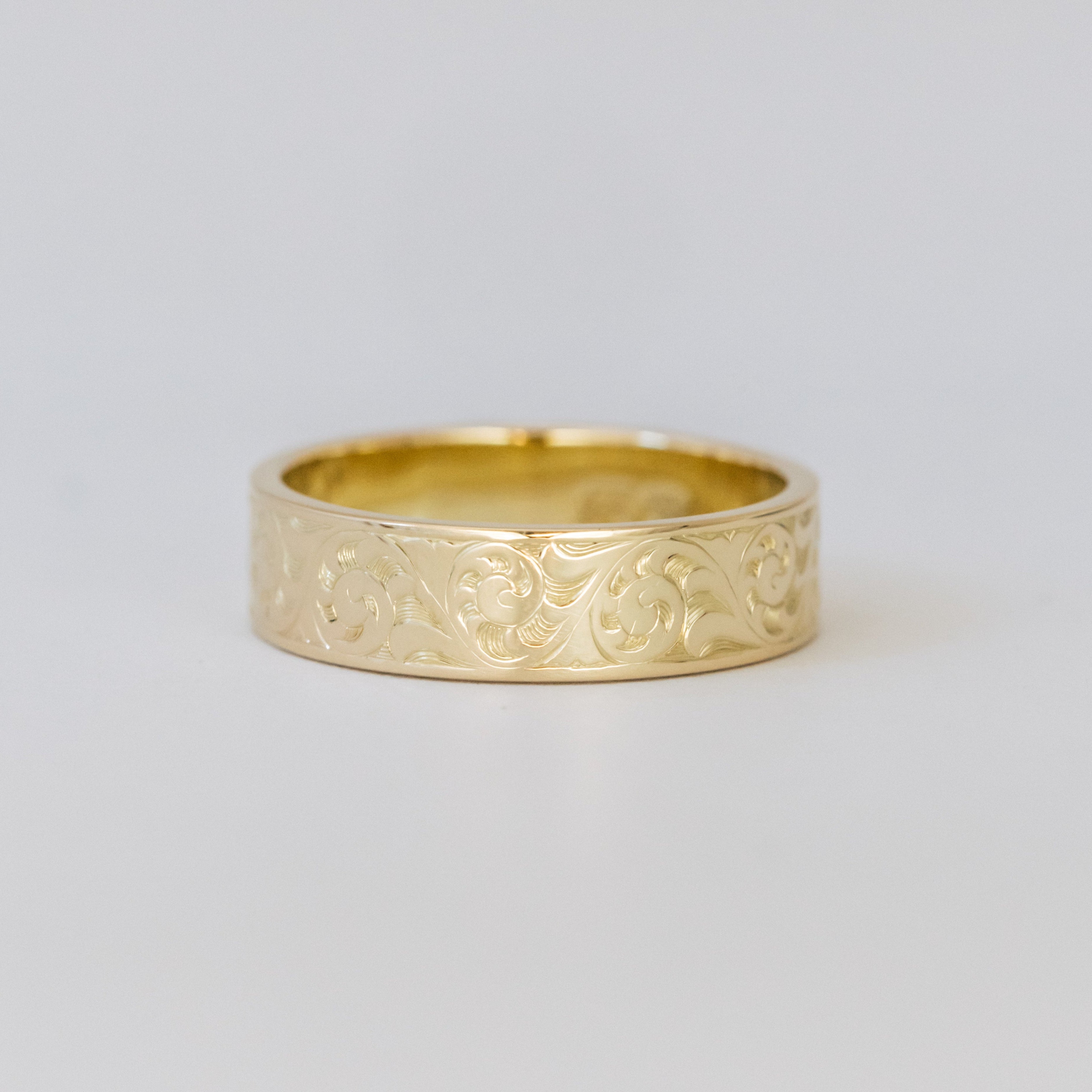 Gold ring with intricate design on a light gray background