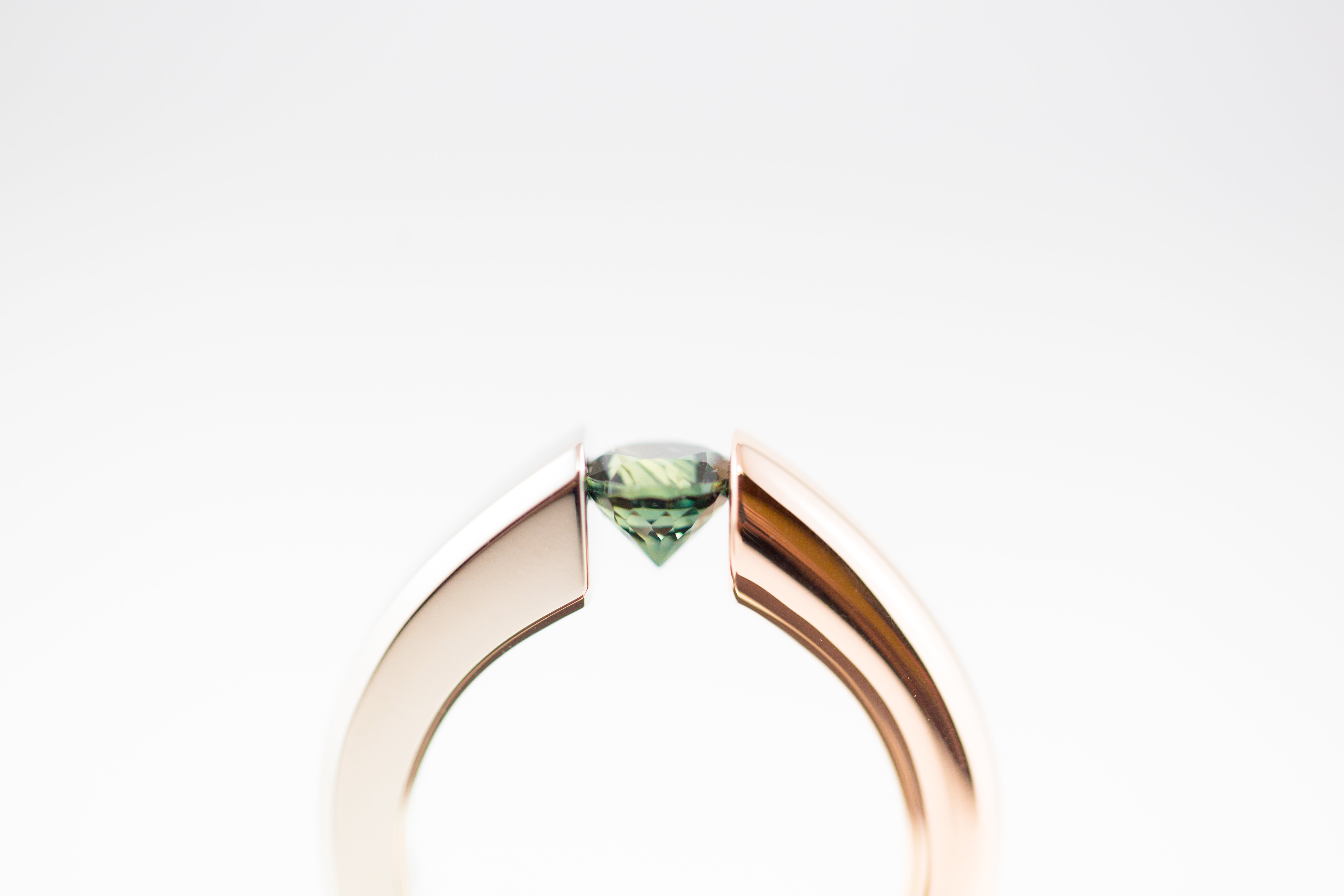 close up of custom tension set ring with a emerald stone